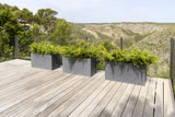 Gray Jort fiberstone planter by Pottery Pots displayed in a natural outdoor setting, showcasing its sleek design.