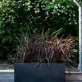 Black Fiberstone Jort planter from Pottery Pots with a textured surface and modern design, ideal for indoor or outdoor use.